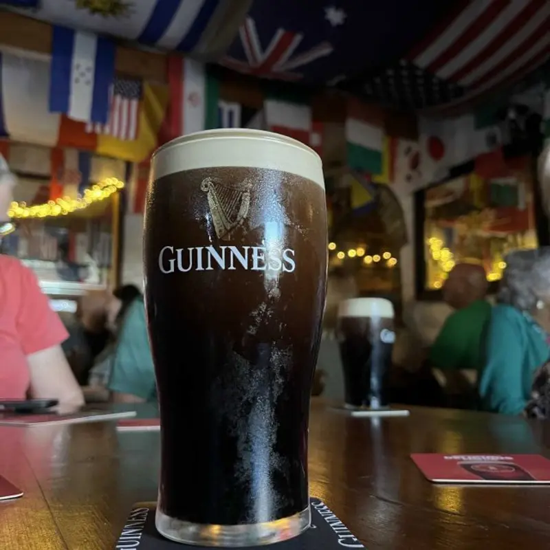 Pint of Guinness on the bar inside Stanford Village Inn with international flags on the ceiling and fairy lights