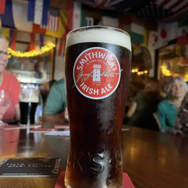 Pint of Smithwick's Irish Ale on the bar inside Stanford Village Inn with flags and warm lighting